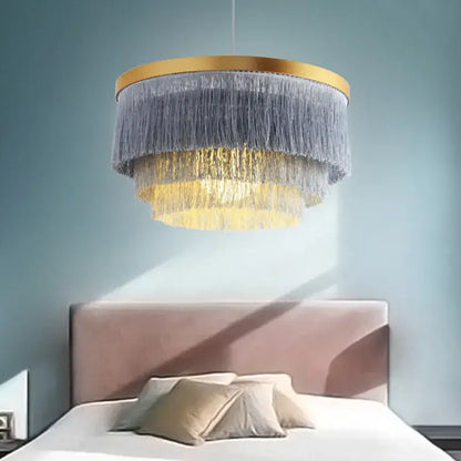 Bohemian gold tiered chandelier with gold-toned frame and cascading gray and golden fringes for bedroom decor
