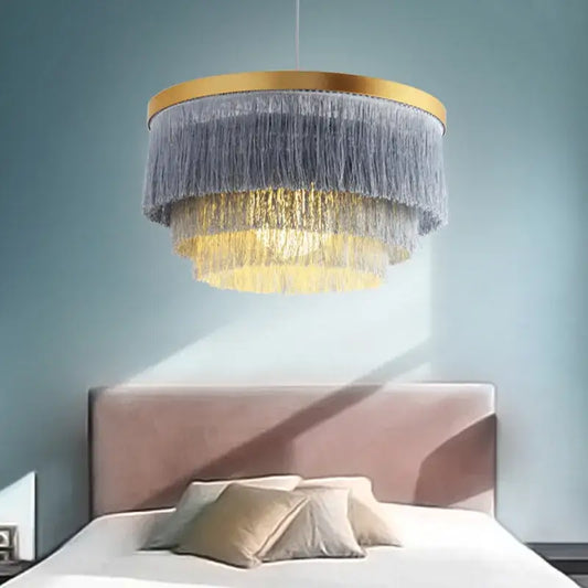 Bohemian gold tiered chandelier with gold-toned frame and cascading gray and golden fringes for bedroom decor