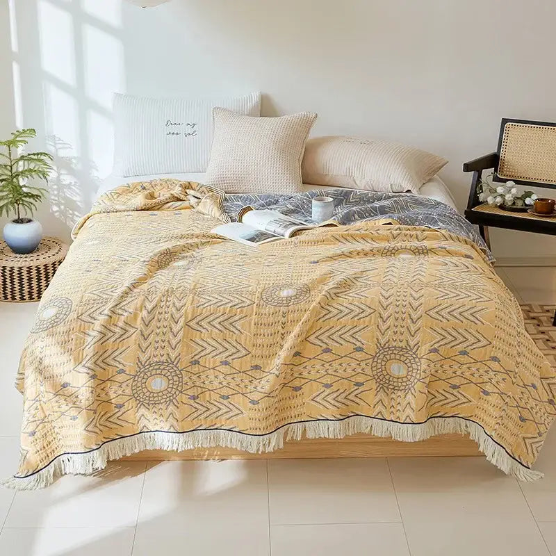 A soft yellow decorbites bohemian cotton throw blanket with gray and black geometric patterns and fringed edge