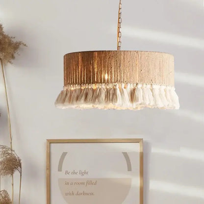A cylindrical pendant light with textured gold finish and cream tassels from decorbites bohemian hemp rope 3 pack