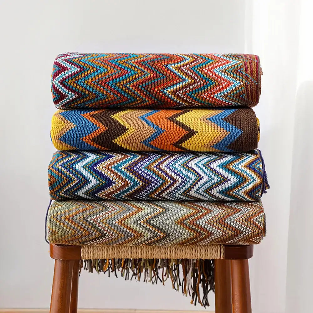 Stacked decorbites bohemian knit tassel blankets with vibrant multicolored zigzag patterns and fringe detailing