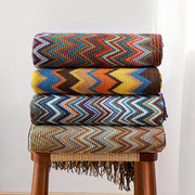 Stacked decorbites bohemian knit tassel blankets with vibrant multicolored zigzag patterns and fringe detailing