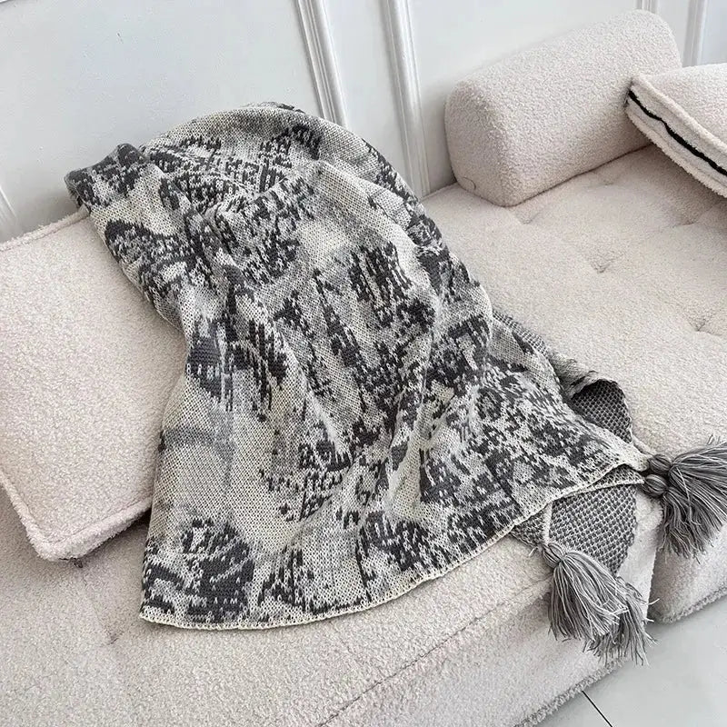 A decorbites bohemian knitted blanket in soft gray and black with tassels for earthy tones bedroom decor