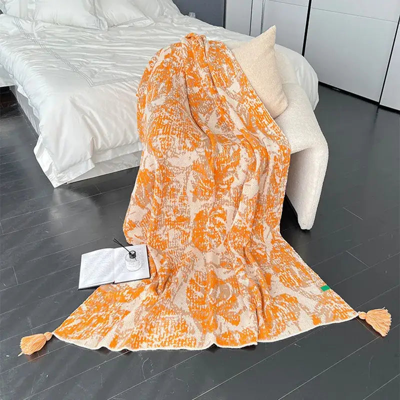 A cozy decorbites bohemian knitted blanket in orange and cream with tassels for earthy tones bedroom decor