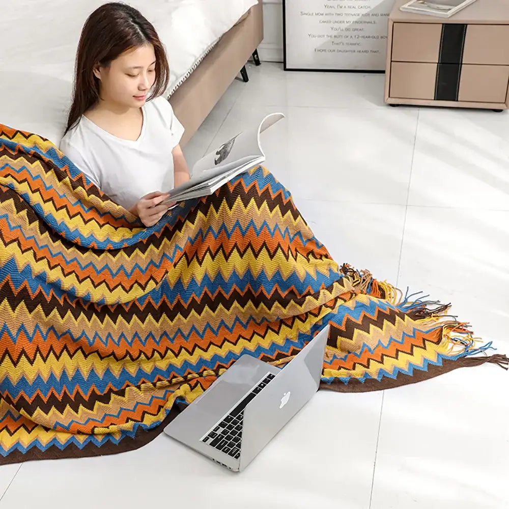Bohemian knitted blanket with vibrant orange yellow blue and brown zigzag pattern and fringed edges for living room use