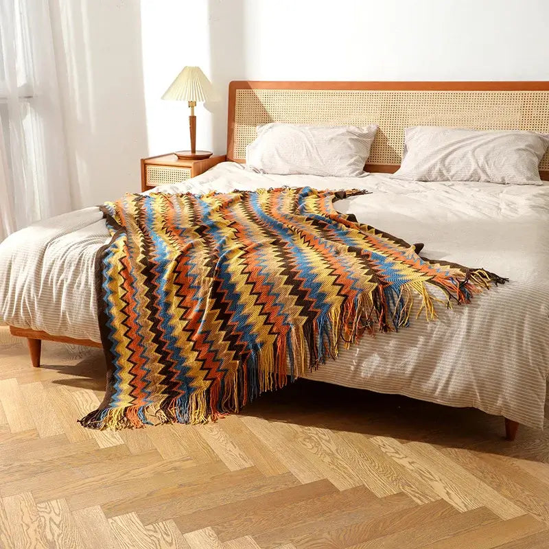 Bohemian knitted blanket with vibrant multicolor zigzag pattern and soft knitted yarn fringe for living room use