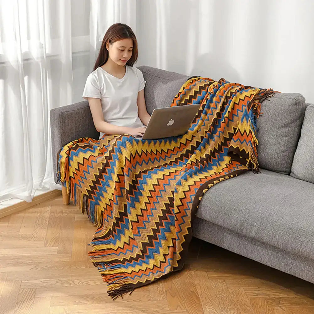 Bohemian knitted blanket with vibrant orange yellow blue and brown zigzag pattern and fringed edges for living room use