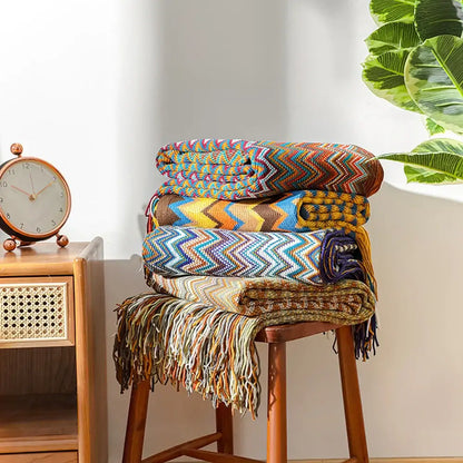 Stack of colorful bohemian knitted blankets with zigzag pattern and fringed edges for living room use