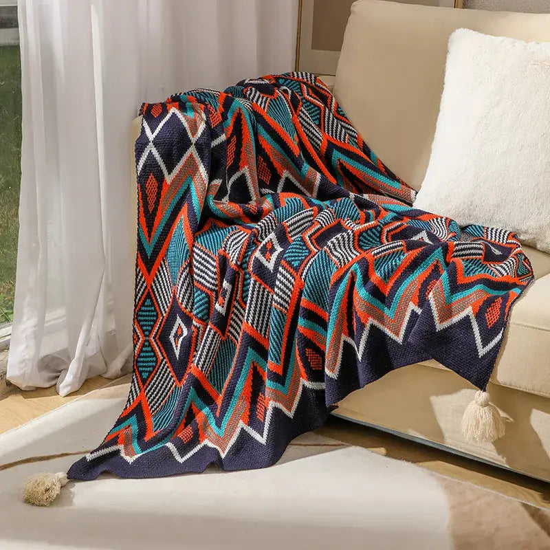 Bohemian knitted throw blanket in cream with bold navy blue teal orange geometric patterns and tassels on corners