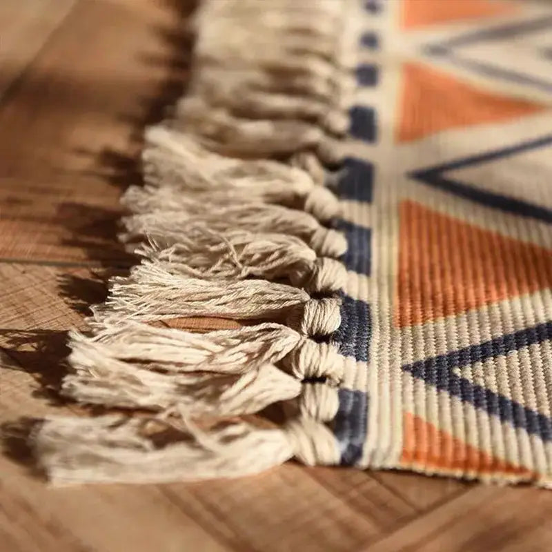 Beige cream-colored fringe with woven geometric pattern in orange and navy on a bohemian linen plaid cotton weave rug runner