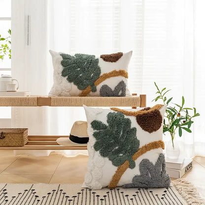 White rectangular plush cushion cover with textured bohemian loop yarn appliqué in green brown and gray leaf patterns
