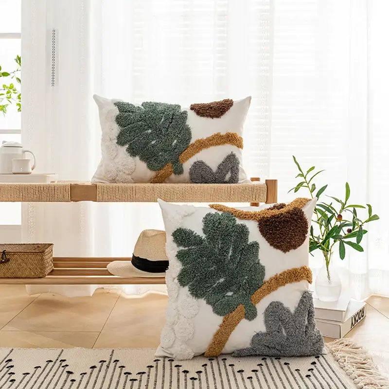 White rectangular plush cushion cover with textured bohemian loop yarn appliqué in green brown and gray leaf patterns