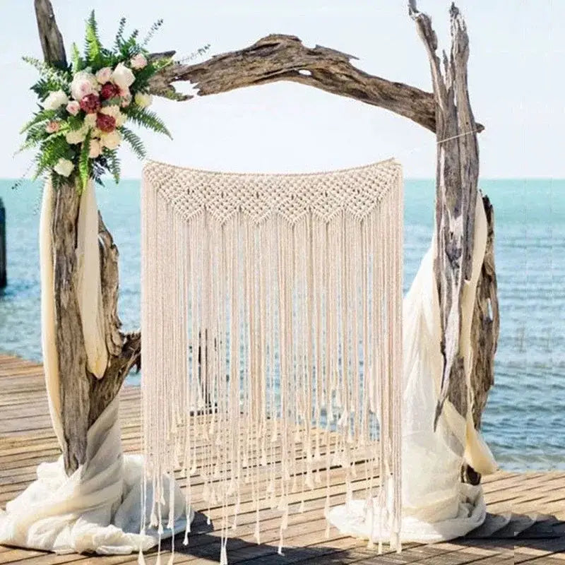 Beige bohemian macrame curtain tapestry with fringe hanging from driftwood arch for living room decorbites decor