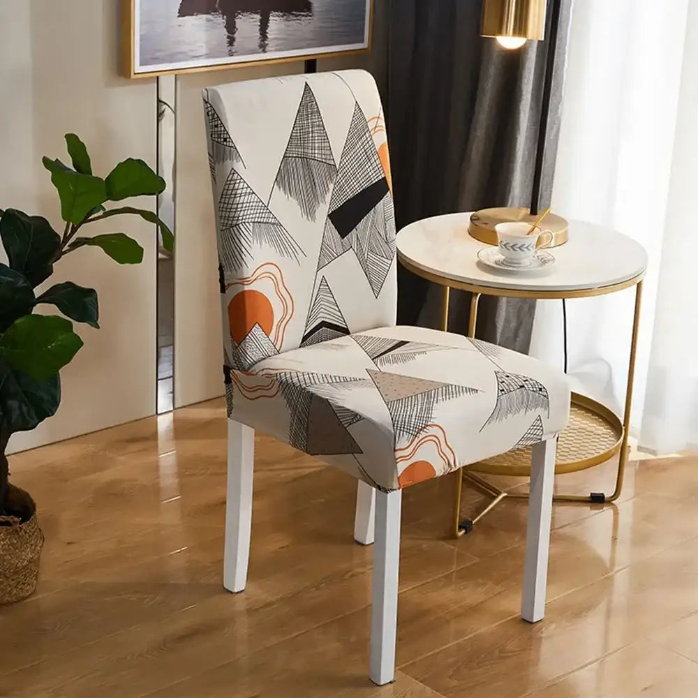 A modern dining chair with a bohemian mandala stretch navy and gold slipcover featuring a geometric mountain pattern