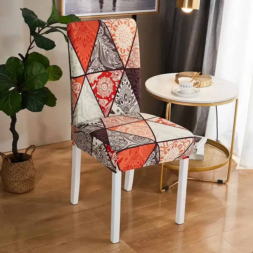 A vibrant patchwork bohemian mandala stretch chair cover with bold orange red cream and intricate black white paisley designs