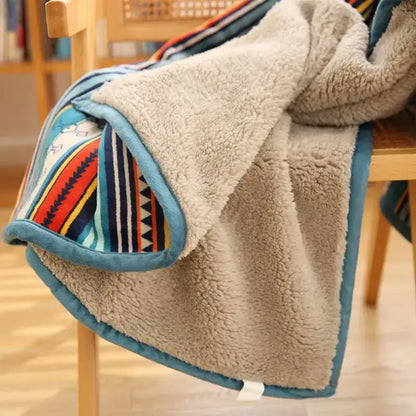 A cozy beige sherpa sofa blanket with colorful striped pattern and teal trim made of winter coral fleece for living room use