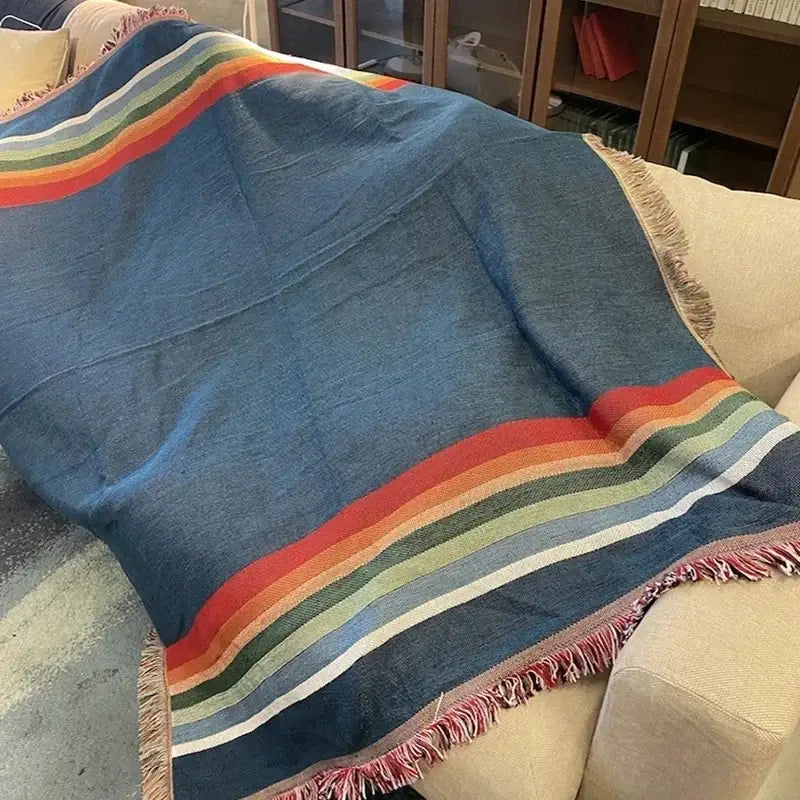 A cozy blue woven bohemian nordic leisure throw with vibrant rainbow stripes and fringed edges for bedroom decorbites