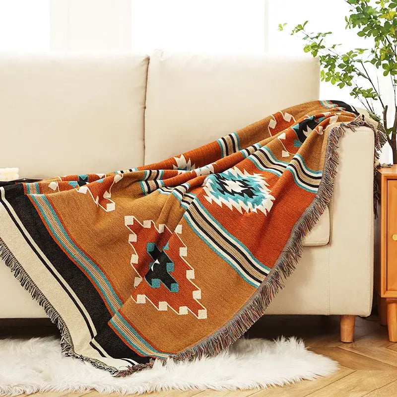 A cozy decorbites bohemian throw blanket in warm orange woven with geometric patterns and fringe detailing