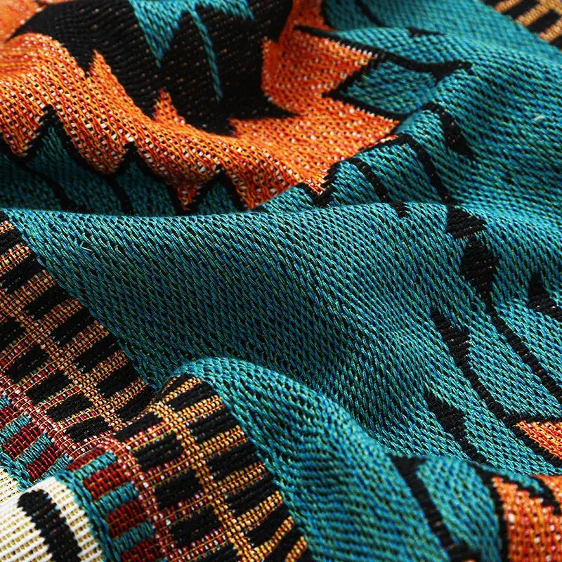 Teal and orange geometric-patterned knitted scarf with black accents paired with decorbites bohemian throw blanket