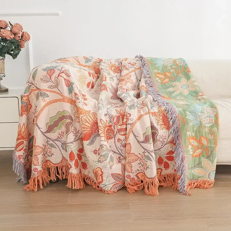 A soft two-toned bohemian sofa blanket in peach and mint green floral pattern with fringed edges by decorbites bohemian