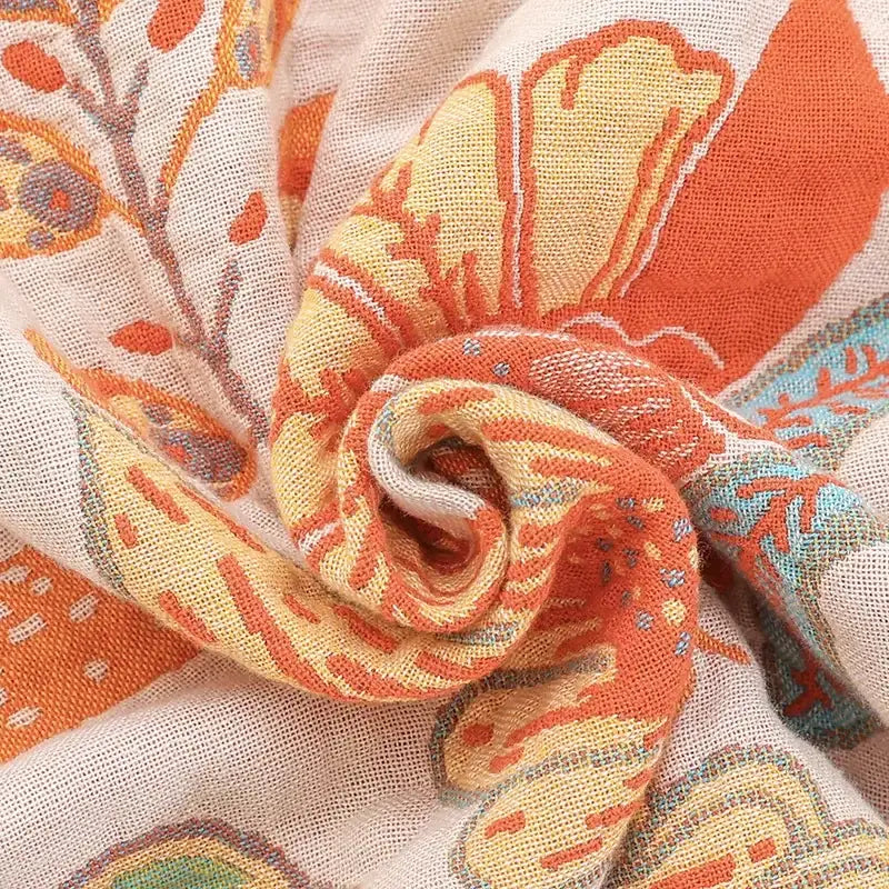 A soft lightweight bohemian sofa blanket with vibrant orange yellow and teal floral pattern by decorbites bohemian decor