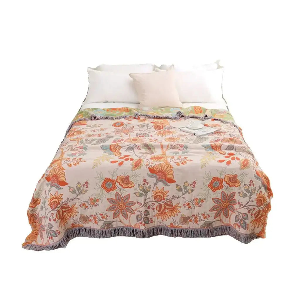 A cream bohemian sofa blanket with vibrant orange green floral pattern and gray fringe from decorbites bohemian