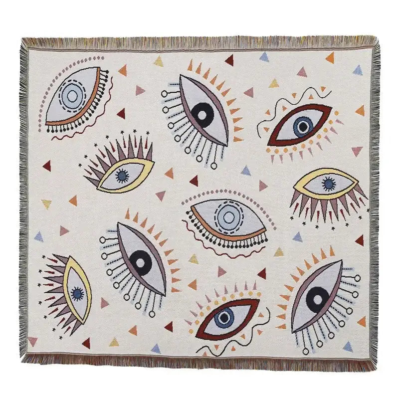 A cream-colored decorbites bohemian outdoor blanket with vibrant eye patterns and fringed edges for living room decor