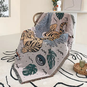 A soft light gray decorbites bohemian outdoor blanket with orange tiger graphic and green monstera leaves for living room decor