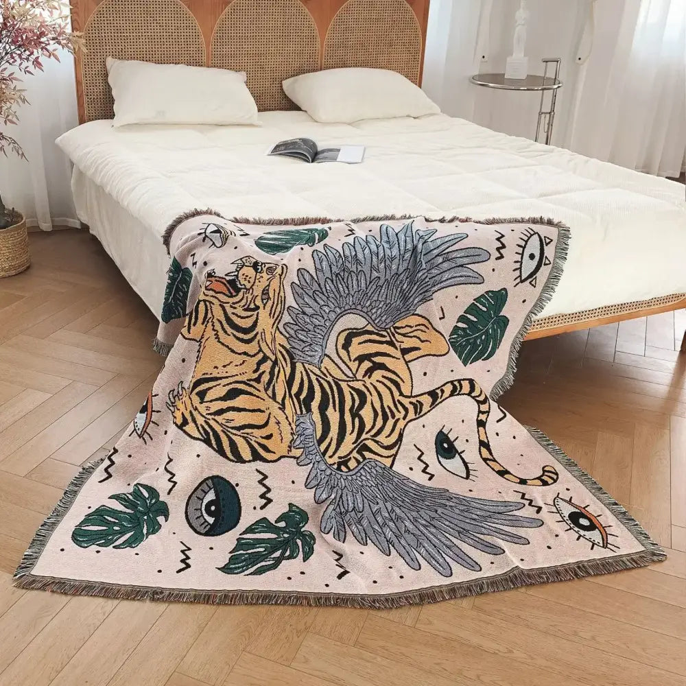 A cream bohemian outdoor blanket by decorbites featuring a vibrant winged tiger and tropical leaves in orange and gray tones