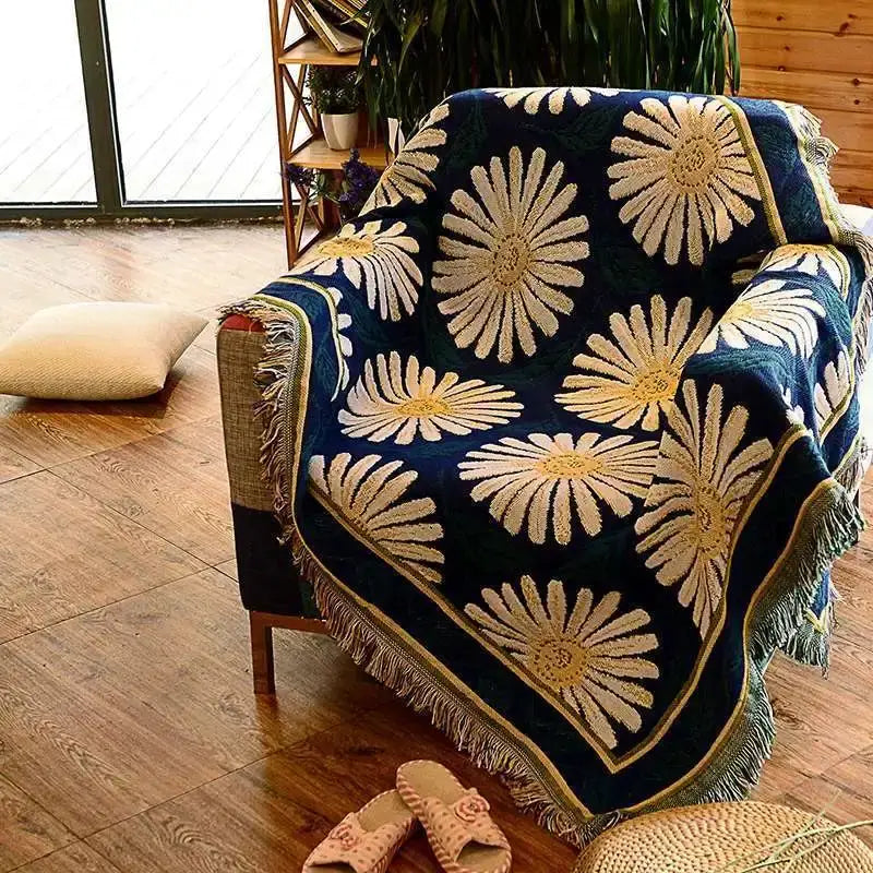 A cozy navy blue decorbites knitted cotton throw blanket with cream and gold daisies and fringed edges for decor