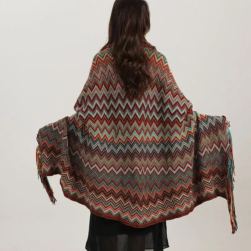 A vibrant bohemian red and teal knit wavy fringe shawl with multicolored zigzag pattern and fringe detailing