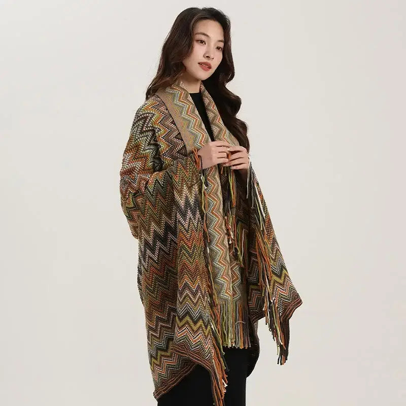 A long open-front knit cardigan in earthy tones with a vibrant zigzag pattern and fringe shawl detailing