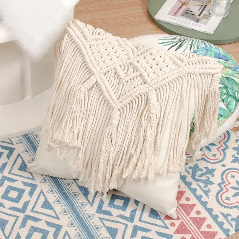 Cream-colored bohemian style beige macrame cushion cover with intricate woven patterns and long fringe decorbites decor