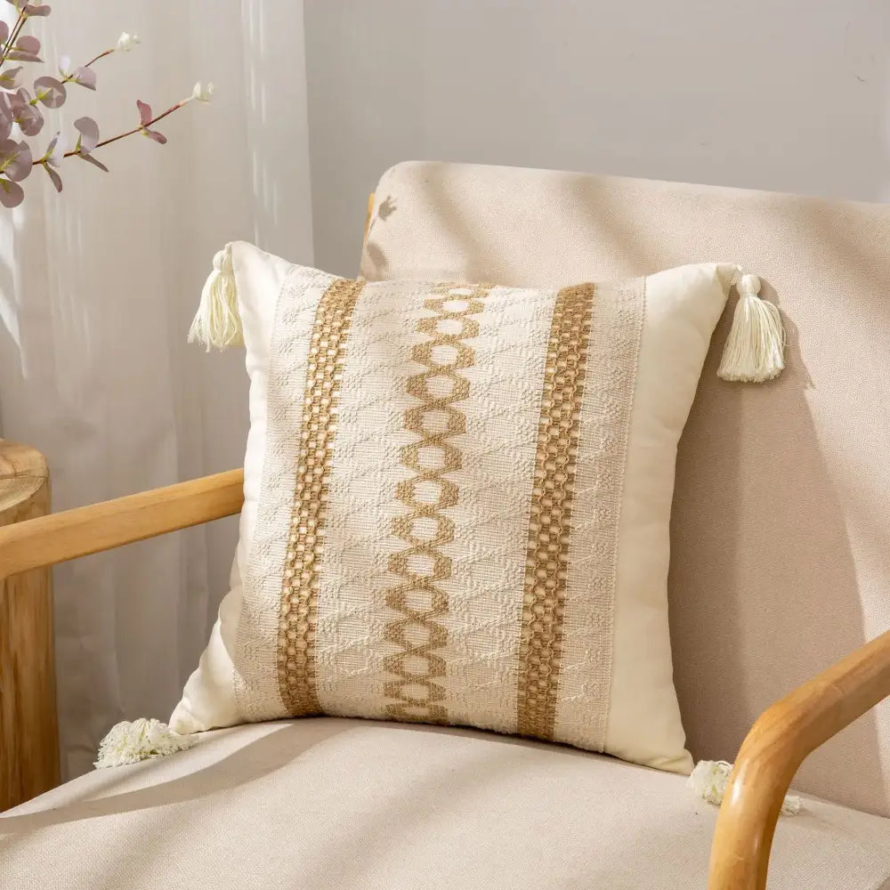 Cream-colored pillow cover with woven gold geometric patterns and tassels by decorbites bohemian style fringed design