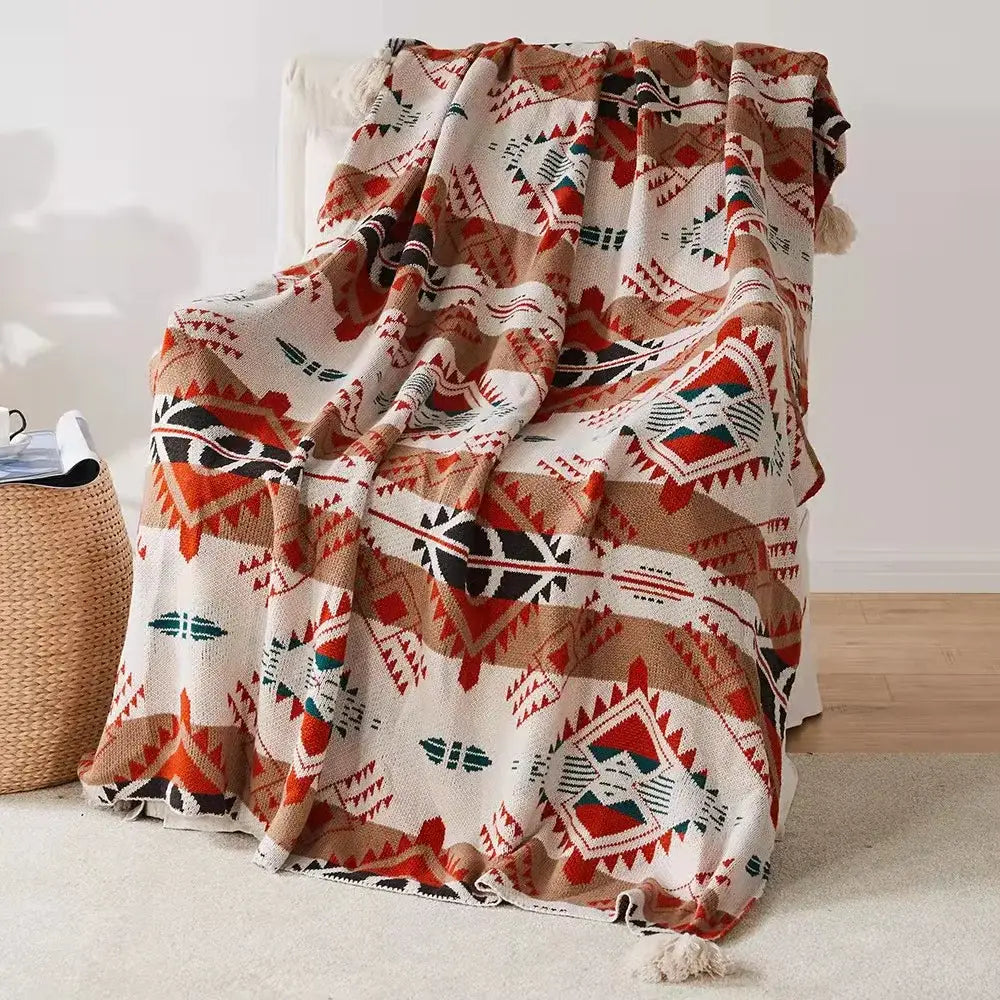 Cream-colored bohemian tassel knit blanket with bold red black teal geometric pattern and tassels for decorbites decor