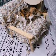 A calico cat stands on a chair draped with a decorbites bohemian tassel knit geometric tapestry throw
