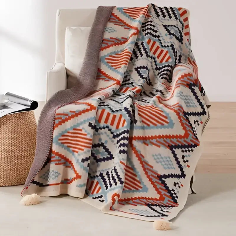 A cozy decorbites bohemian tassel knit blanket with geometric pattern in orange navy blue and cream with tassels