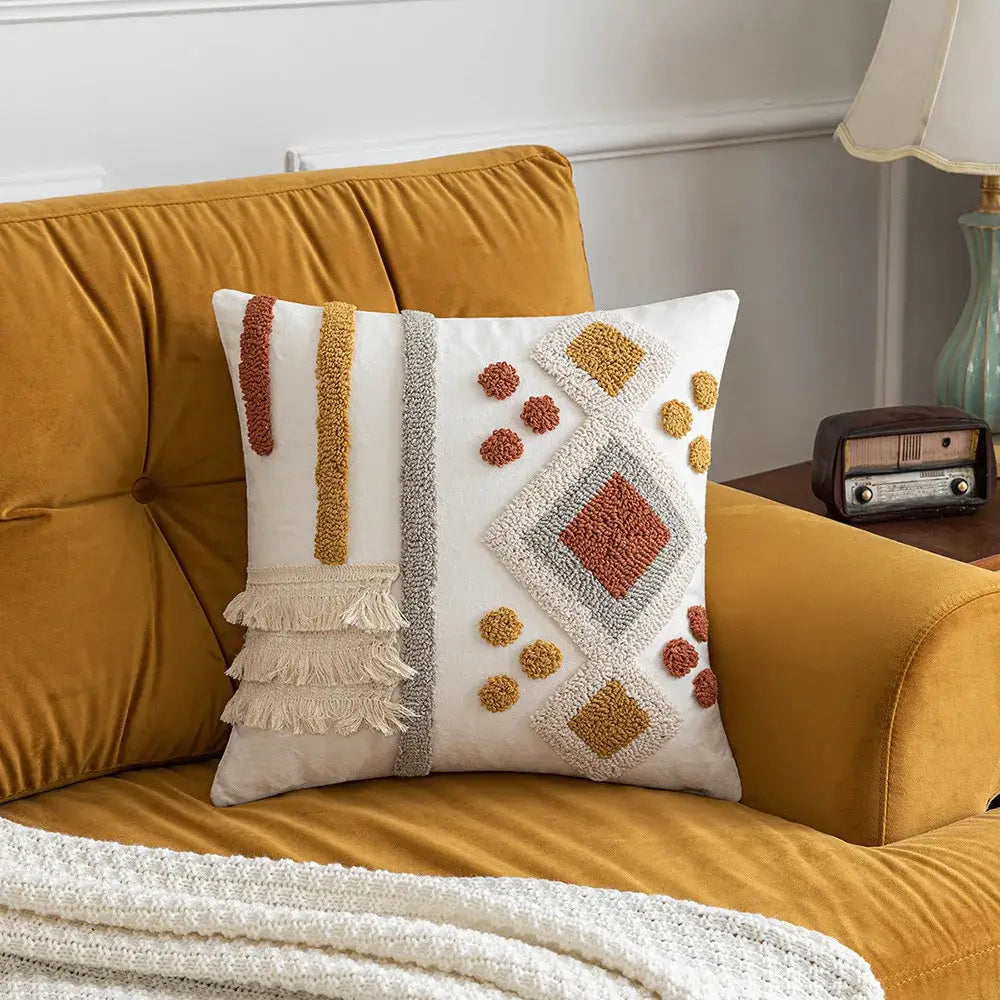 White throw pillow with bohemian tufted tassel design in beige featuring terracotta and mustard geometric patterns and fringe