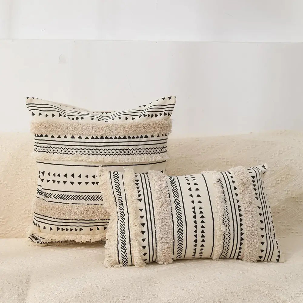 Cream-colored bohemian tufted tassel pillow case with black geometric patterns and fringed edges for living room decorbites
