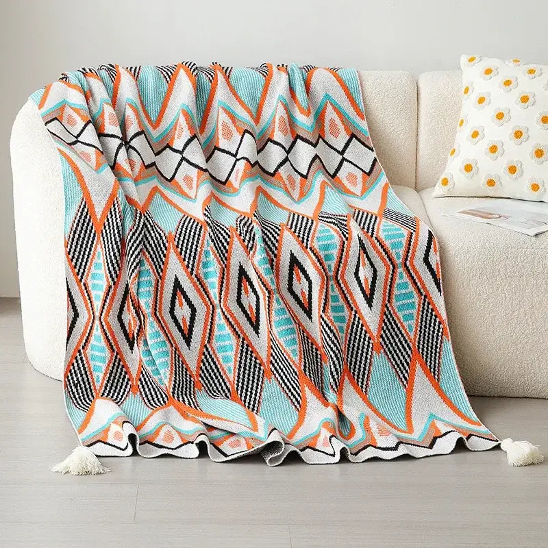 A cozy knitted bohemian winter blanket with bold turquoise orange black and white geometric pattern for decorbites decor