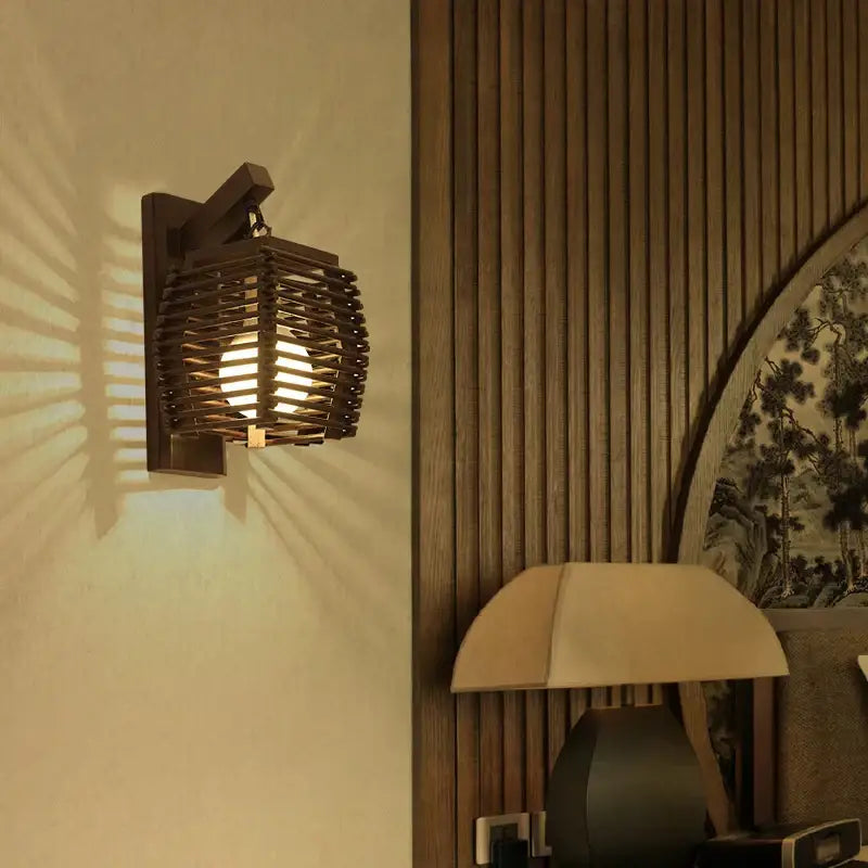 Dark brown bamboo wall sconce light with woven wood slat design and warm glowing bulb for boho corridor decor