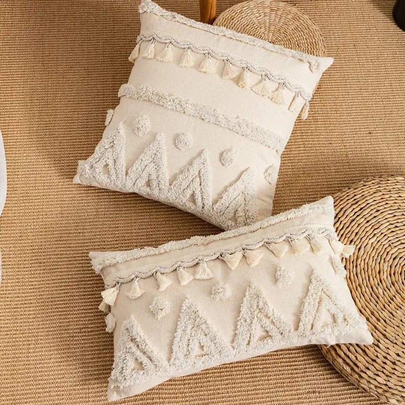 Cream-colored rectangular pillow cover with tufted fringed geometric pattern and tassel trim for living room decor