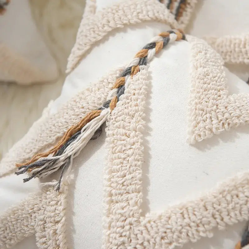 Cream-colored tufted pillow cover with braided tassel in beige gray and tan for living room decor