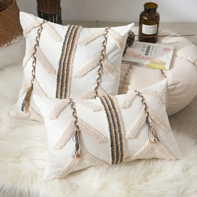 White rectangular tufted pillow cover with beige and brown braided tassels and geometric woven patterns for living room