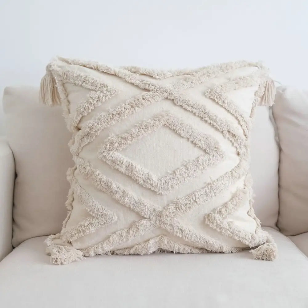 Cream-colored boho beige white pillow cases with textured geometric pattern and tassel fringed decor for living room