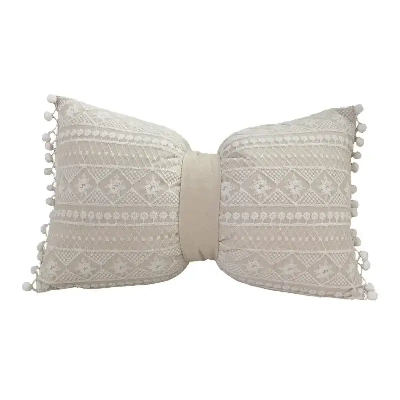 Beige bow-shaped pillow cover with intricate lace pattern and pom-pom trim made of linen cotton for living room decor