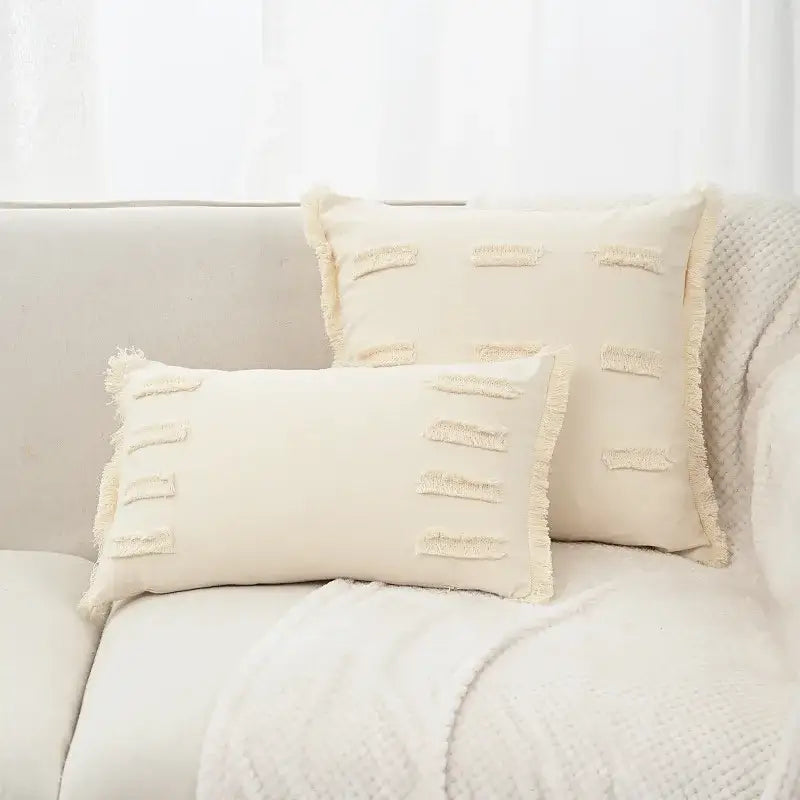 Cream-colored rectangular linen cotton pillow cover with frayed edges and horizontal tassel accents for living room decor