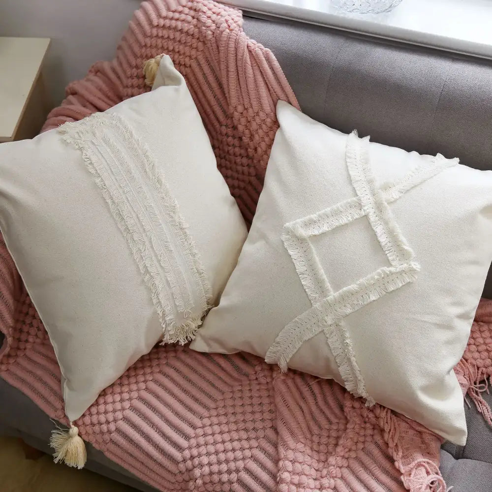 Cream-colored square linen cotton pillow cover with frayed fabric accents and tassels for living room decor