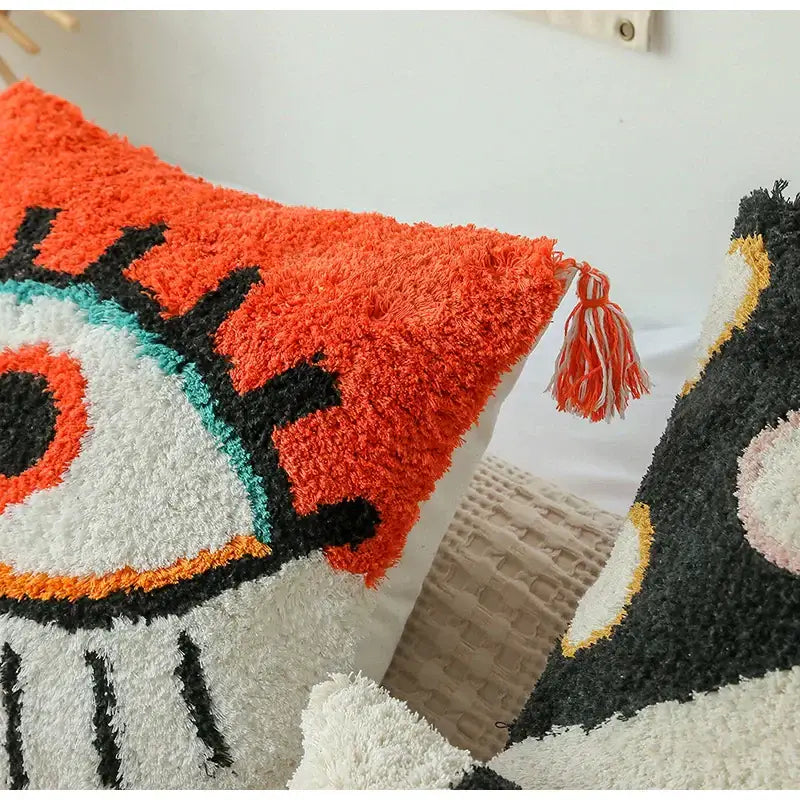 Vibrant orange and white plush cushion cover with boho big eye tufted design featuring black and teal accents