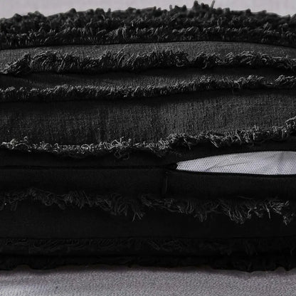 Black distressed fabric pillow cover with tassel striped design and frayed edges featuring a white zipper pull for home decor